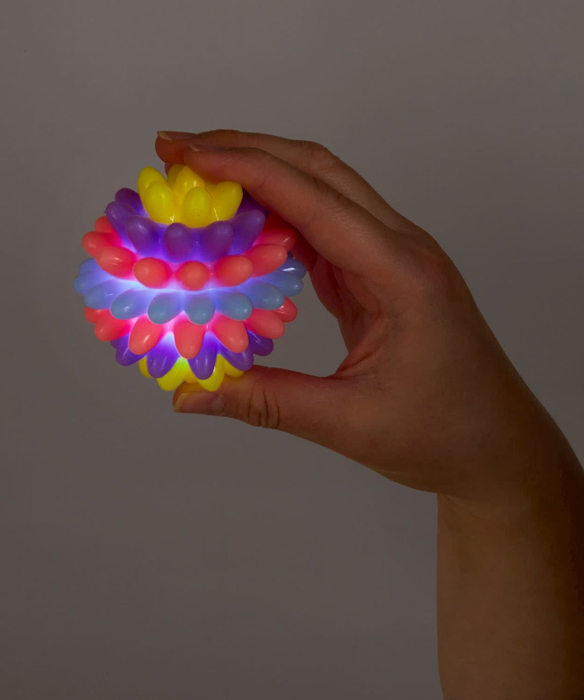 Multi-colored flashing spike ball made of hard rubbery TPR material with a spherical silhouette.