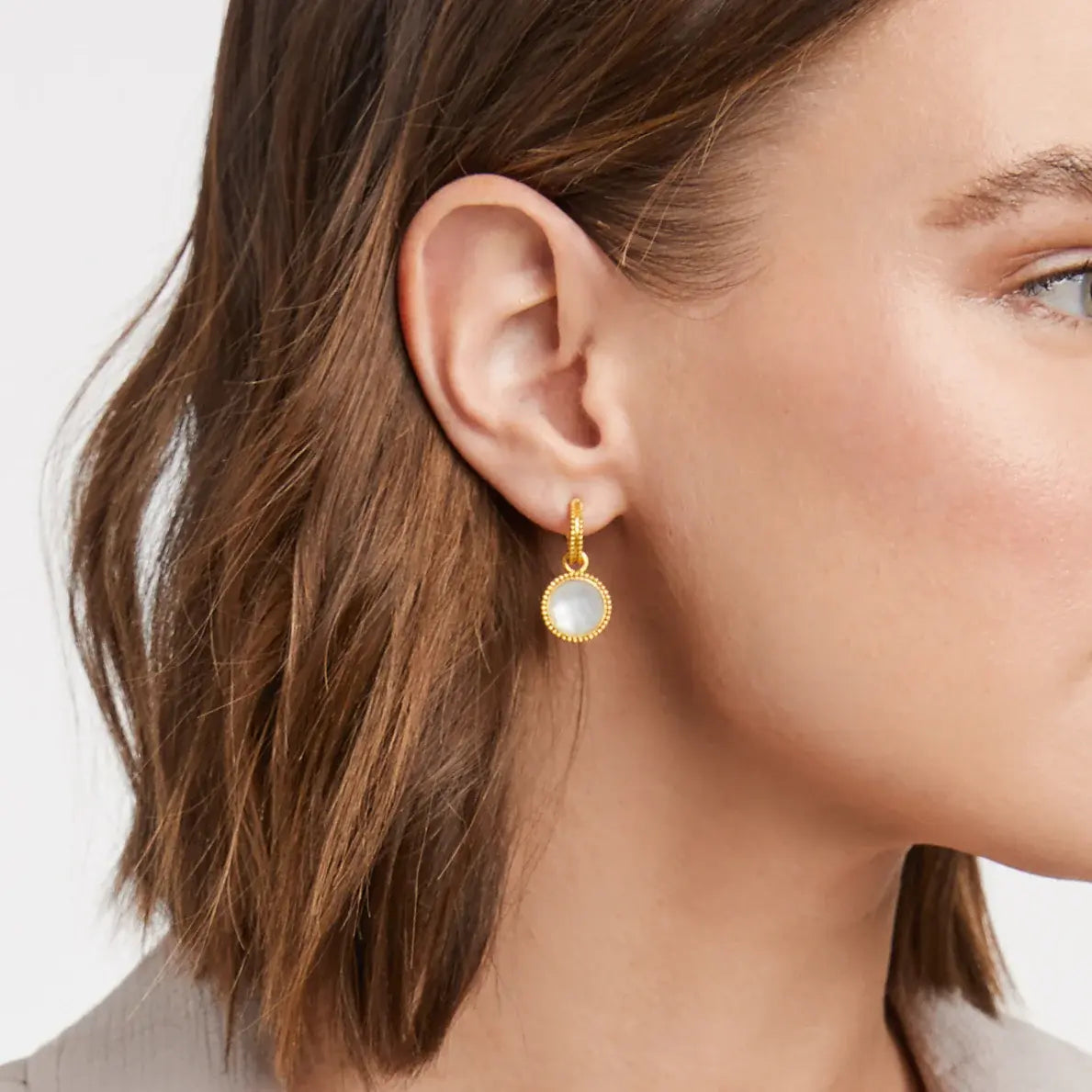 Gold-plated hoop earring with mother-of-pearl charm featuring a fleur-de-lis design