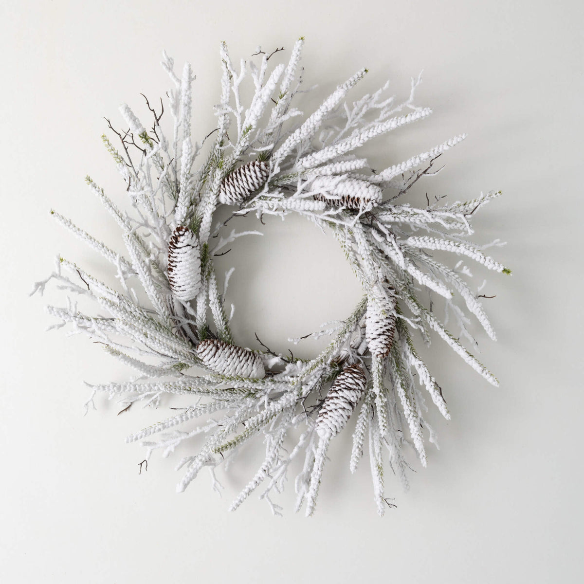 Flocked pine twig wreath with faux snow coating in neutral tones