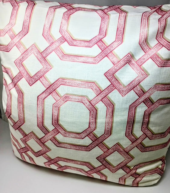 A 24x24 inch pillow with a white background and a repeating geometric pattern in pink and gold.
