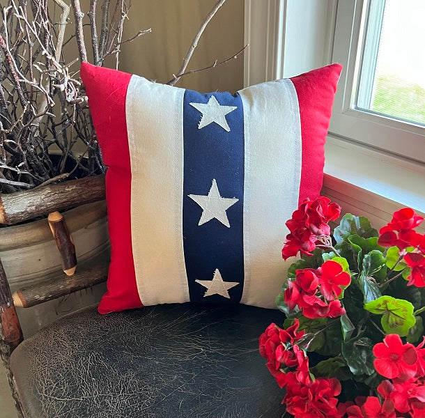 Square vintage pillow featuring a stars and stripes pattern in red, white, and blue tones.