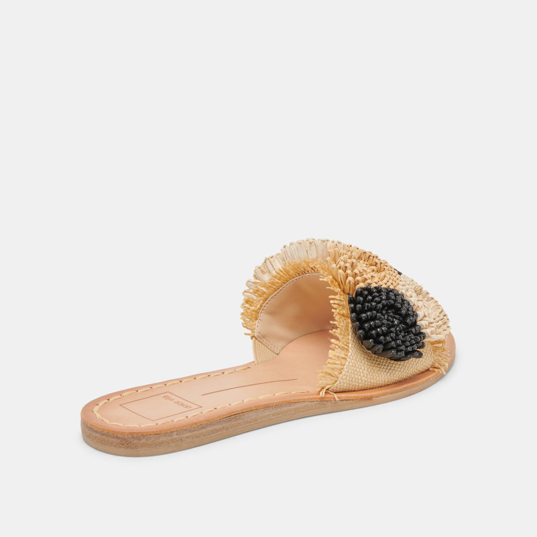 Danela flat slide sandal with a raffia upper, fringe edges, and a black beaded floral accent.