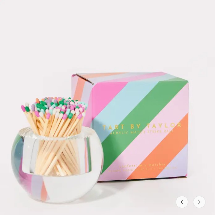 Round acrylic match striker with colorful matches next to a striped gift box.