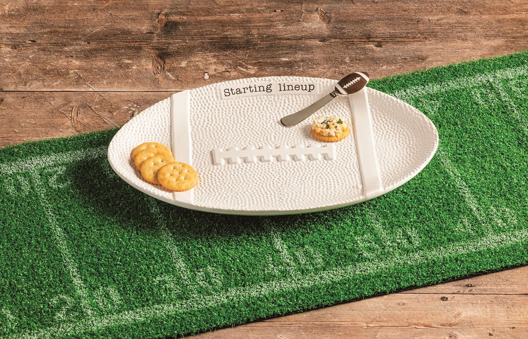Ceramic football-shaped platter with textured detail paired with a stainless steel spreader featuring an enamel handle.