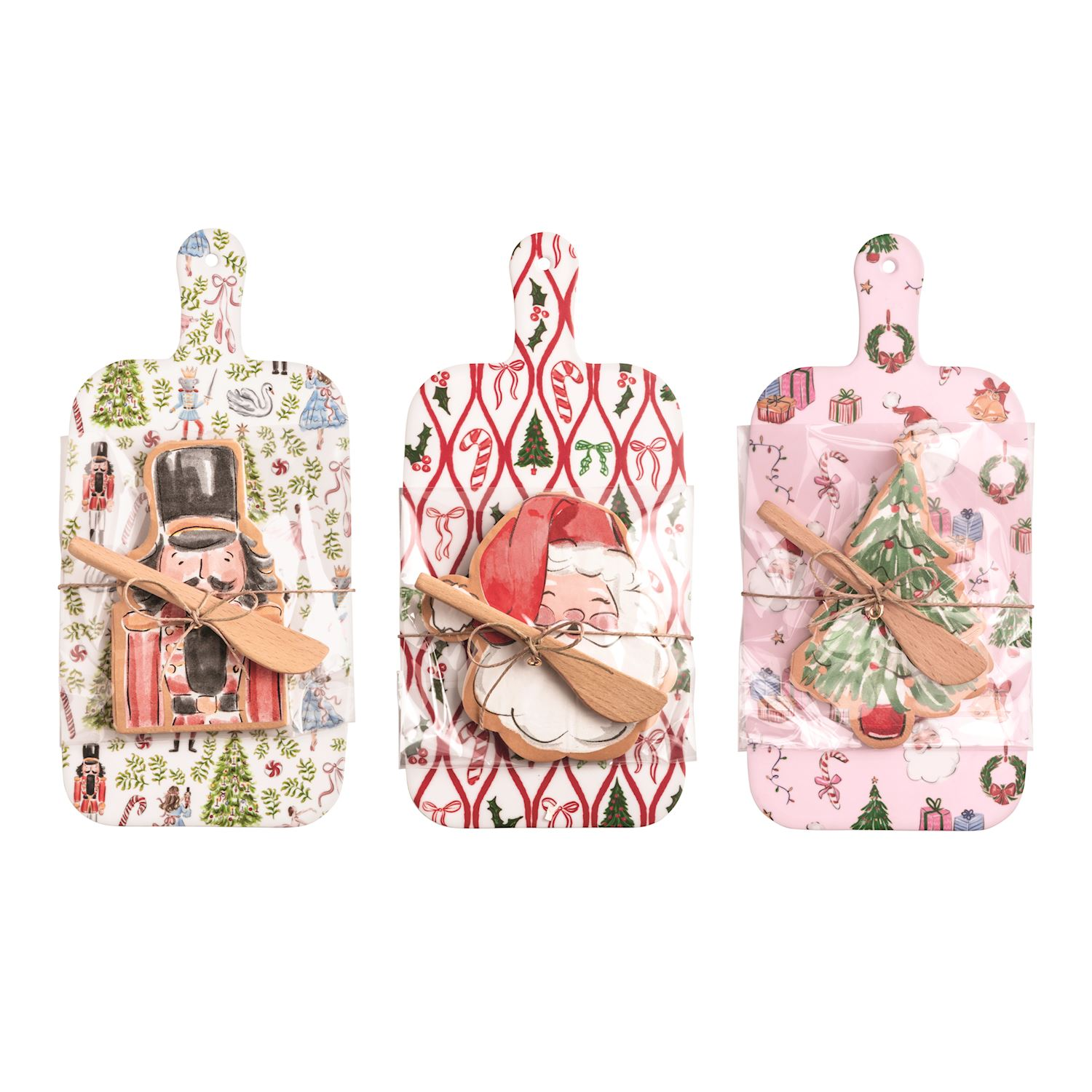 Three Christmas melamine paddle boards with nutcracker, Santa, and tree napkins and wooden spreaders.