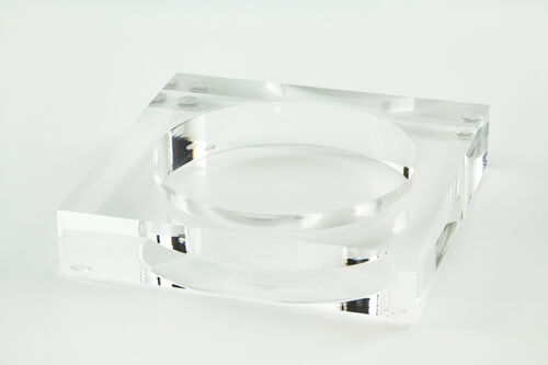 Square clear lucite wine bottle coaster with a circular recessed center.