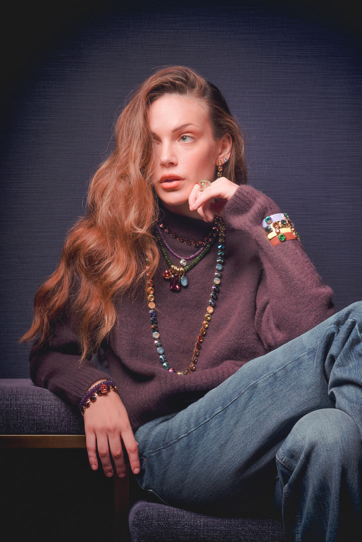 Woman wearing the Mckinney Necklace, a long strand of colorful crystals and beads on antique gold.