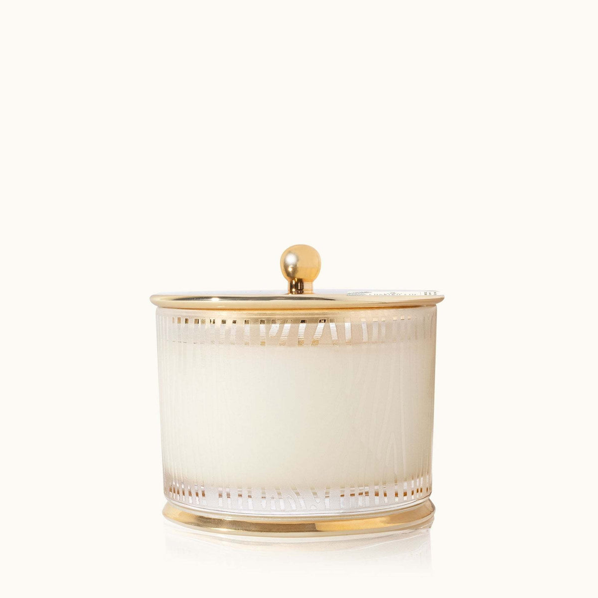 Medium poured candle with frosted wood grain finish, glistening gold lid, and gilded base.