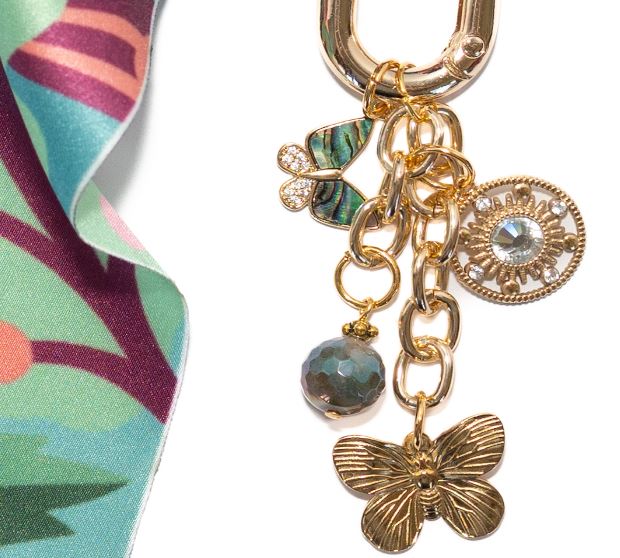 Costa floral bag charm featuring a colorful flower motif on a metallic chain link.