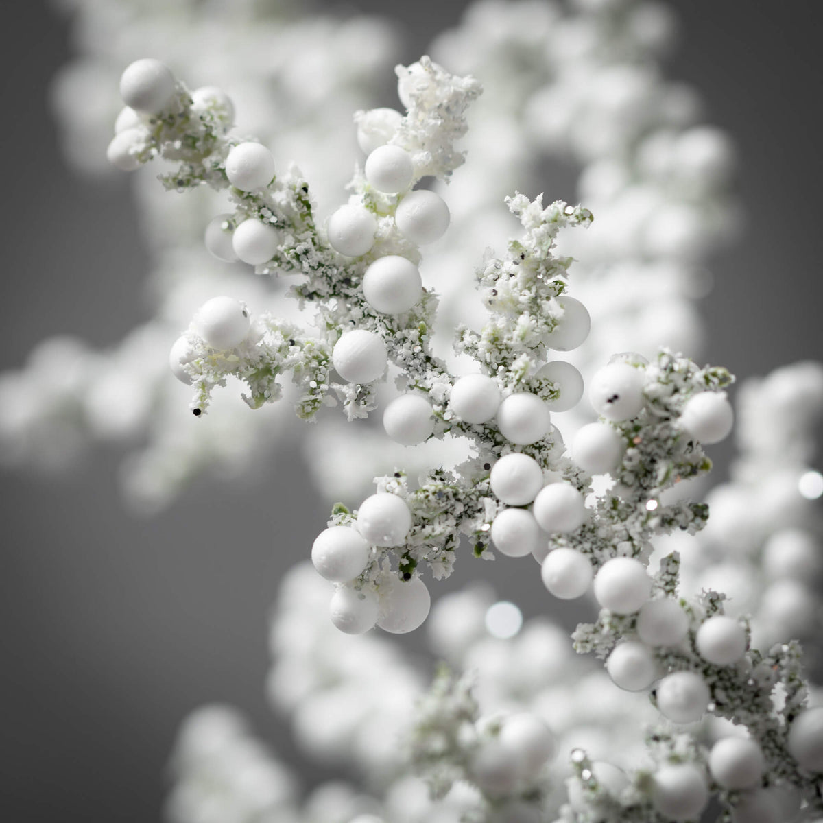Faux frosted juniper berry spray with neutral pine twigs on a plastic stand.