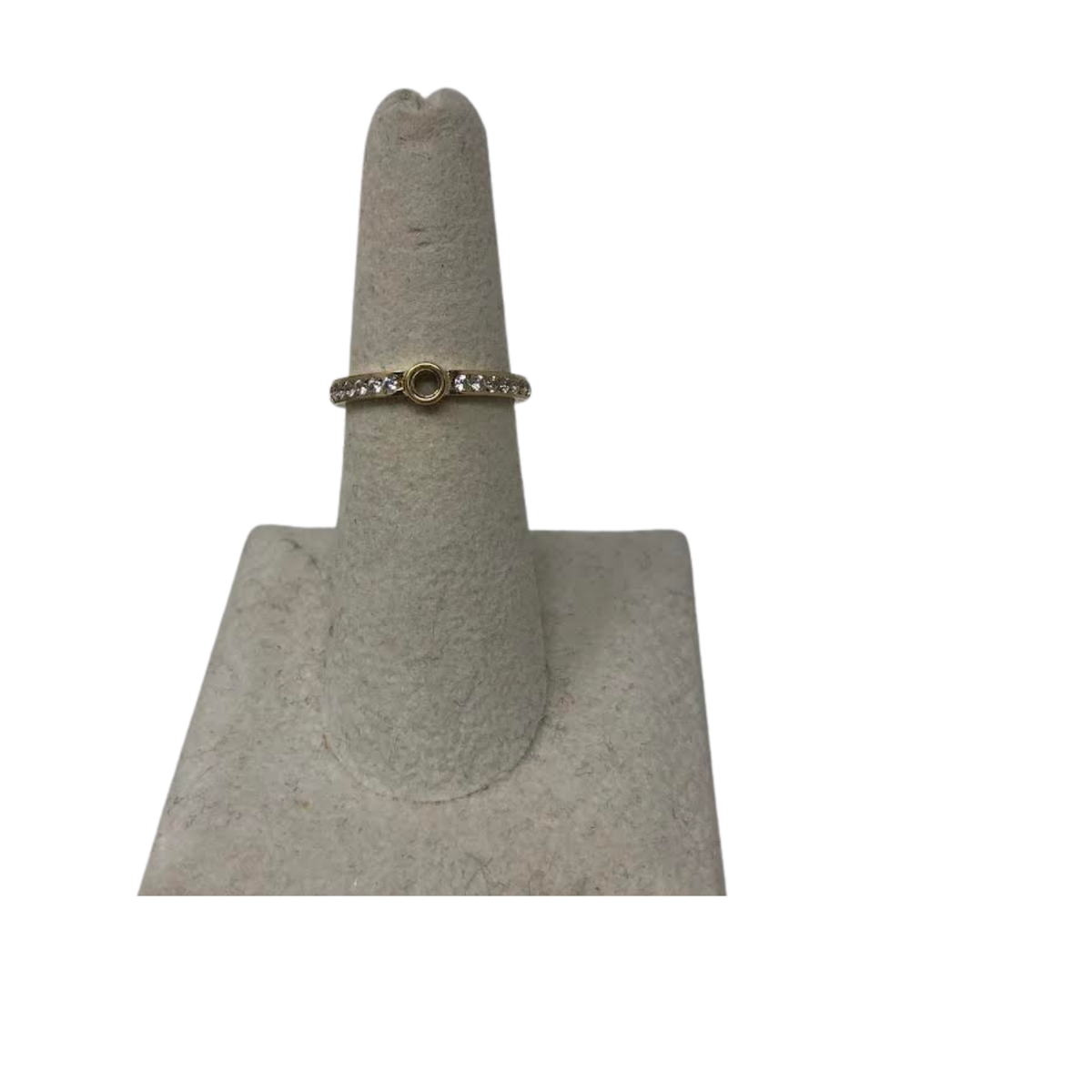 Gold eternity band ring with clear stones and a central circular bezel setting on a display stand.