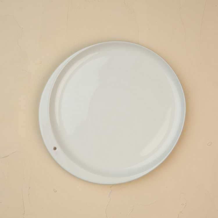 Top-down view of a minimalist white ceramic Celebration Circle plate with a single small hole.