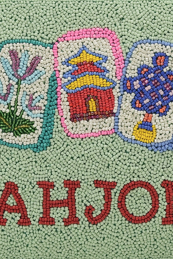 Close-up of a mint green hand-beaded clutch featuring colorful Mahjong tile designs and red text.