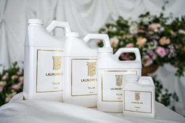 Four white bottles of Thomas Blonde Laundry Detergent in various sizes with gold Tulum labels.