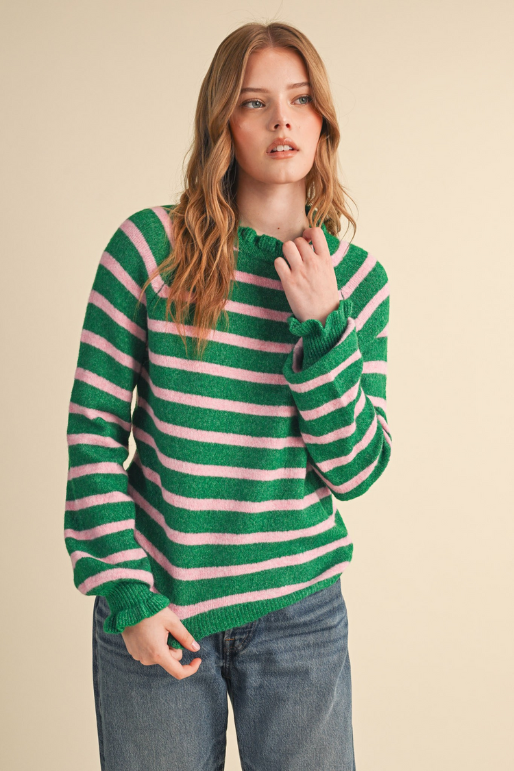 Woman wearing the Charlie green and pink striped sweater with ruffled neckline and cuffs.