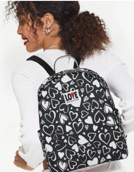 Woman wearing the Endless Love Backpack, a black and white heart-patterned bag with a logo patch.