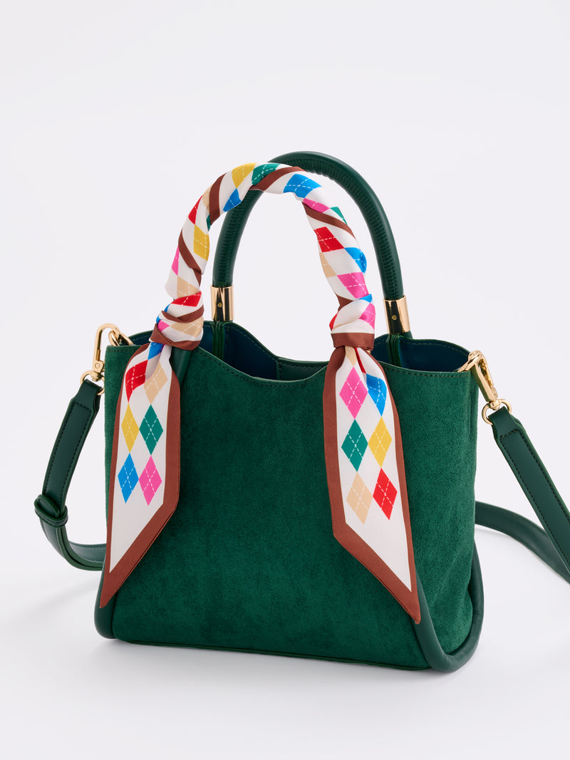 Ivory Argyle Twilly Scarf with colorful diamond pattern wrapped around a green suede handbag handle.