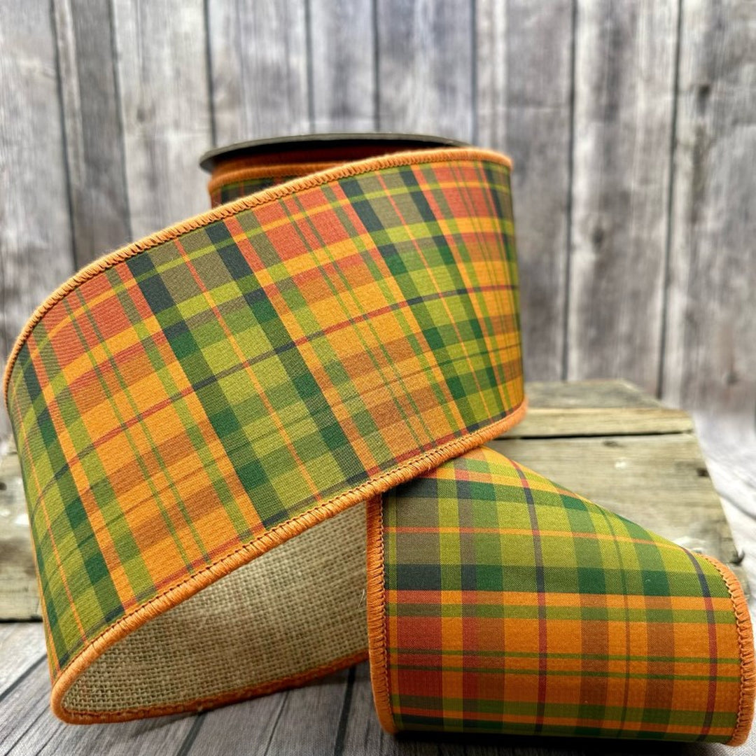 4-inch wide orange and green autumn plaid dupion ribbon with a burlap back on a wooden surface.