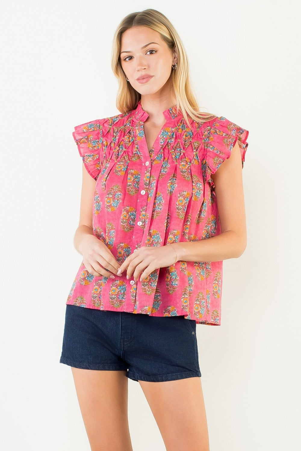 Woman wearing the Natalie Flutter Sleeve Floral Pattern Top in pink with dark denim shorts.