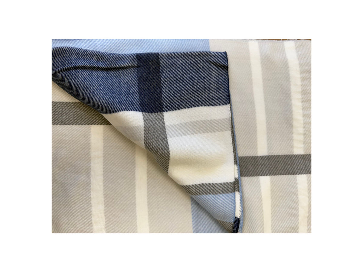 Folded Scottish plaid cashmere scarf in shades of navy blue, grey, and white.