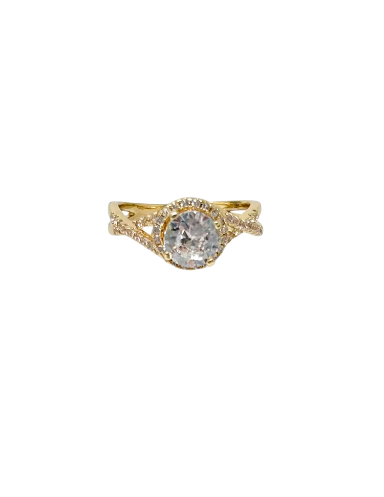 Gold fashion statement ring with a round center stone, halo setting, and pavé crisscross band.