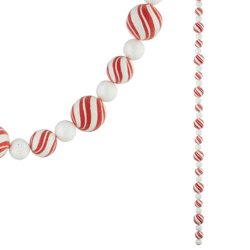 Green foam garland with red plastic peppermint candy ornaments hanging on a white background.