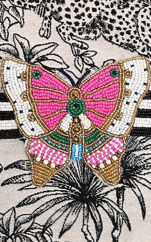 Close-up of a hand-embellished beaded butterfly on a jacquard tote with a black and white pattern.