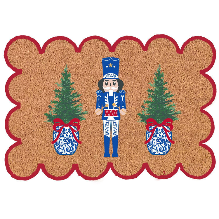 Scalloped coir doormat with a blue nutcracker between two Christmas trees in ginger jars.