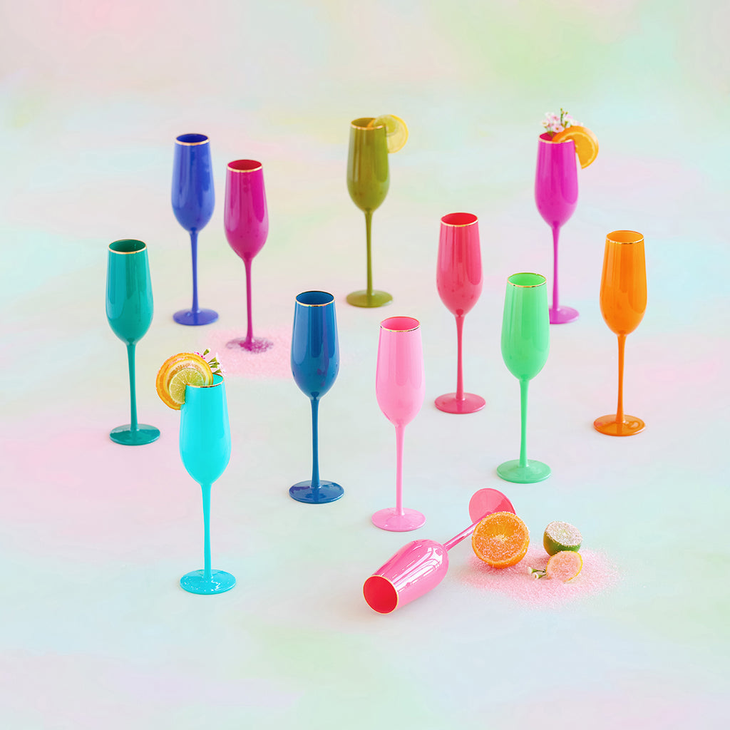 Vibrantly colored handblown glass champagne flutes with gold rims in various bright hues.