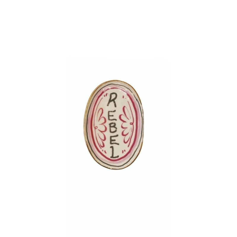 Oval stoneware magnet with a pink border and the word REBEL in black hand-lettering.