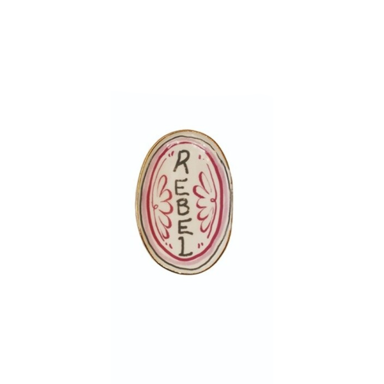 Oval stoneware magnet with a pink border and the word REBEL in black hand-lettering.