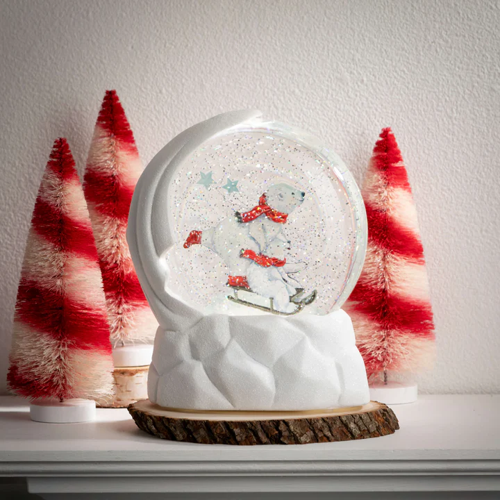 Set of three red and white candy stripe bottlebrush trees next to a polar bear snow globe.