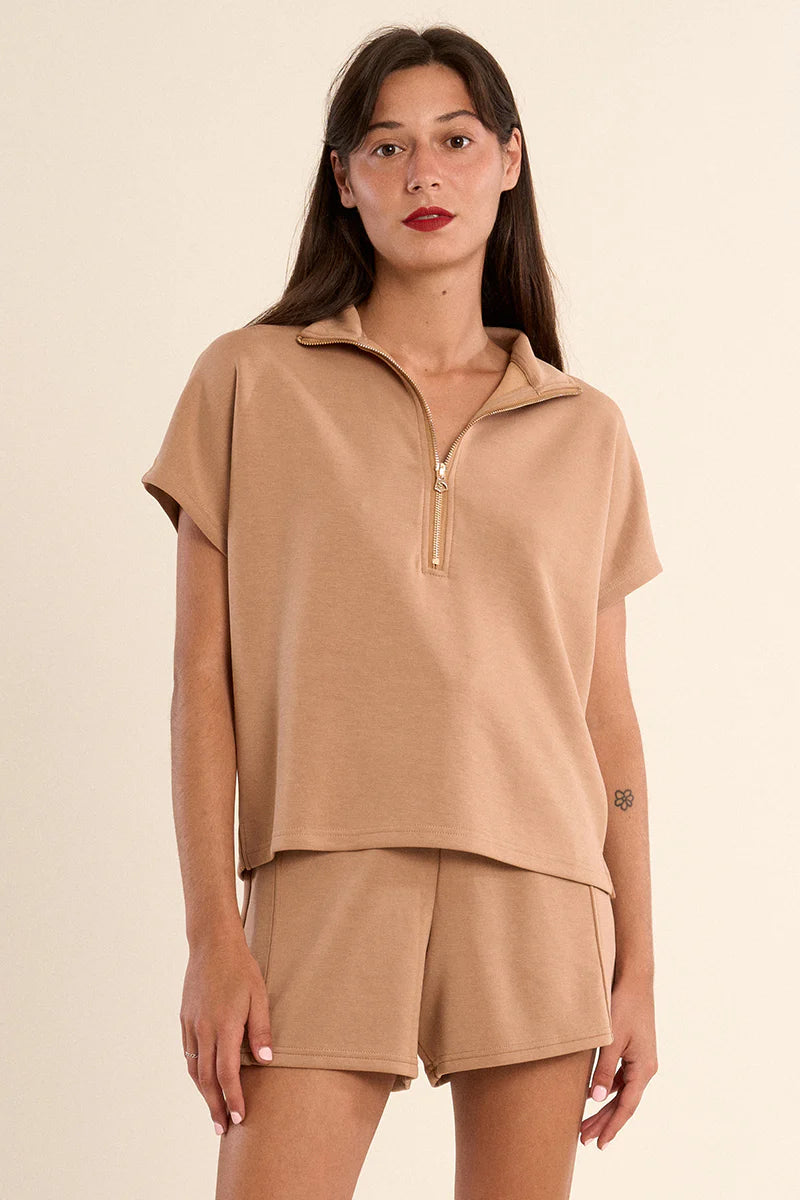 Woman wearing a tan Cassey ladies knitted sleeveless sweat with a half-zip collar and matching shorts