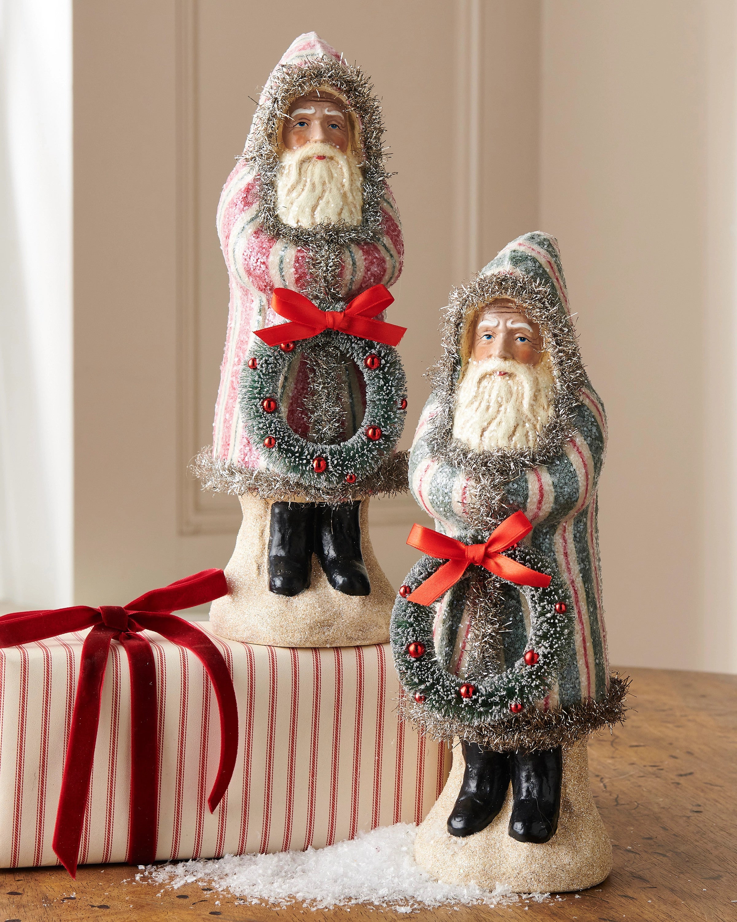 12-inch Old World Santa figurines in striped coats holding wreaths, standing on a wooden surface.
