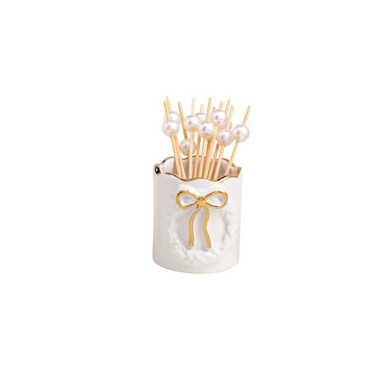 White stoneware toothpick caddy with gold bow motif and pearl-topped wooden toothpicks.