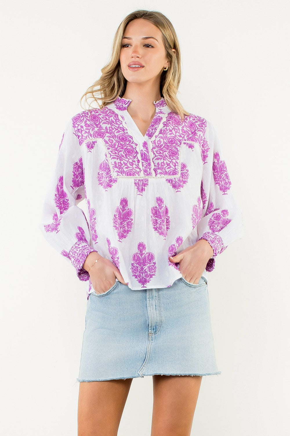 Woman wearing the Amy Long Sleeve Flower Print Top in white with purple floral patterns.