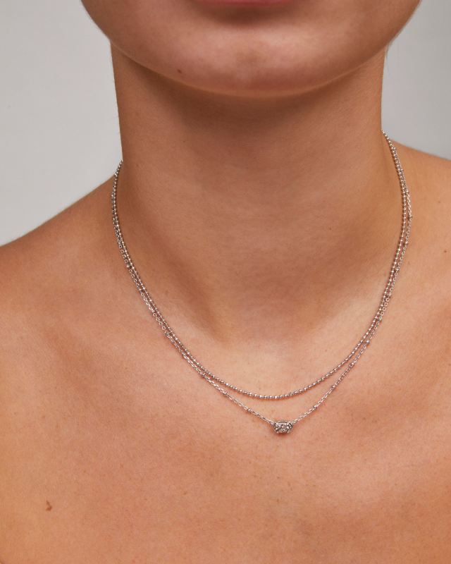 A person wearing the Emilie Multi Strand Necklace, featuring two silver-tone chains and a station.