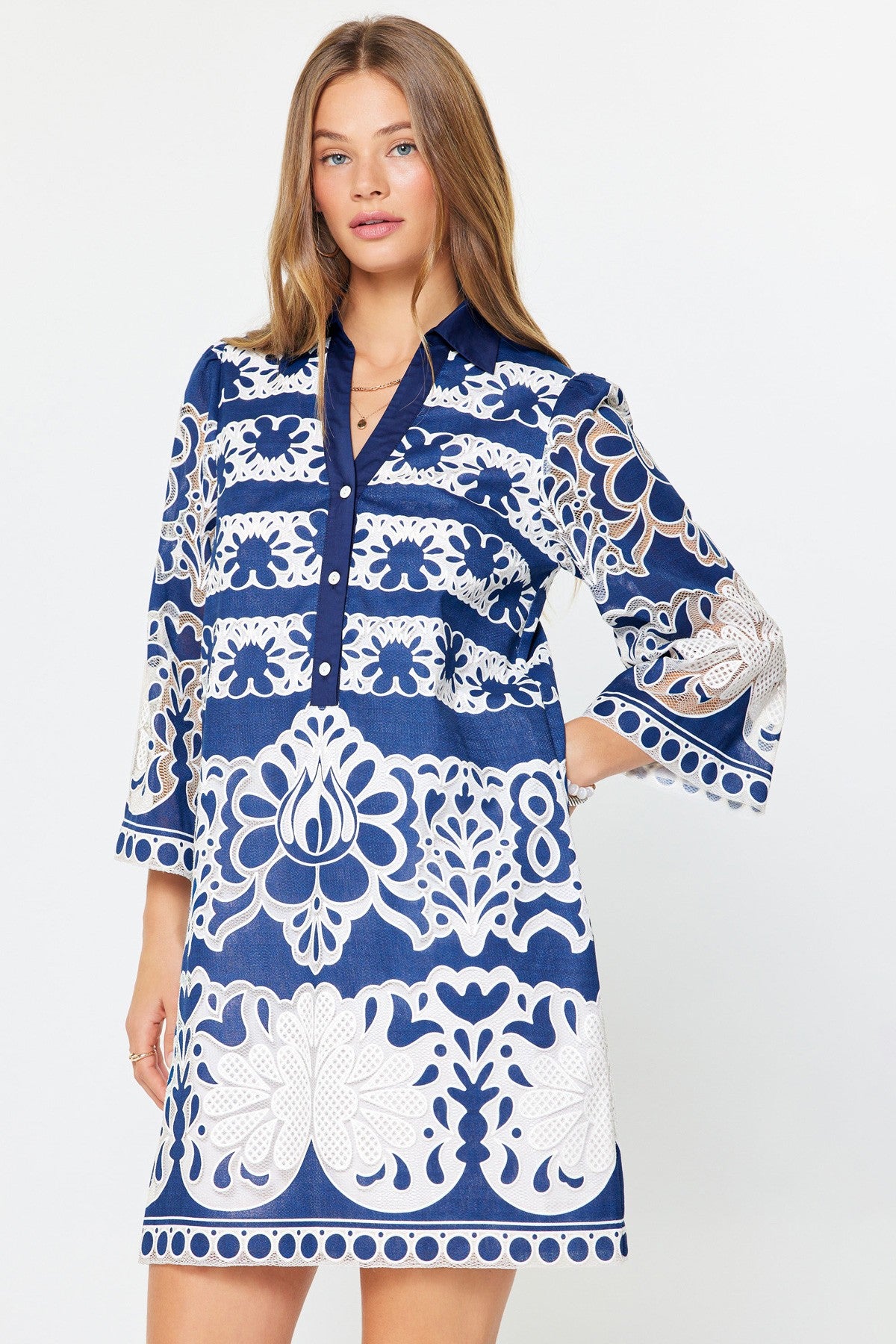 Avery mini dress in beige rayon/poly with floral lace embroidery, collared neckline, button placket, and side pockets.