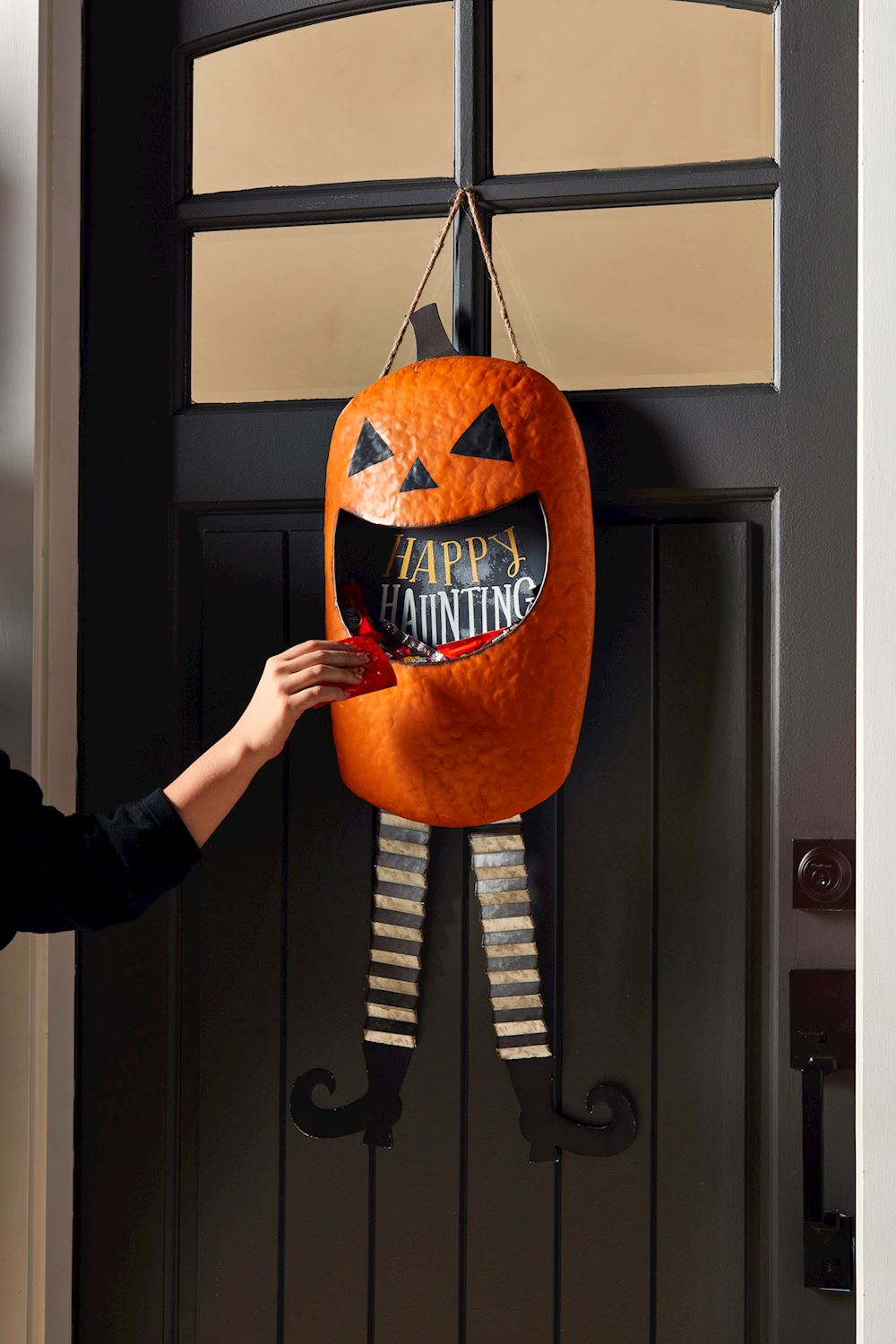 Tin Jack-O-Lantern candy door hanger featuring an orange pumpkin silhouette with a black stem and carved face.