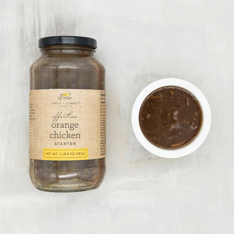 A 24 oz jar of Finch + Fennel Effortless Orange Chicken Starter next to a small bowl of the sauce.