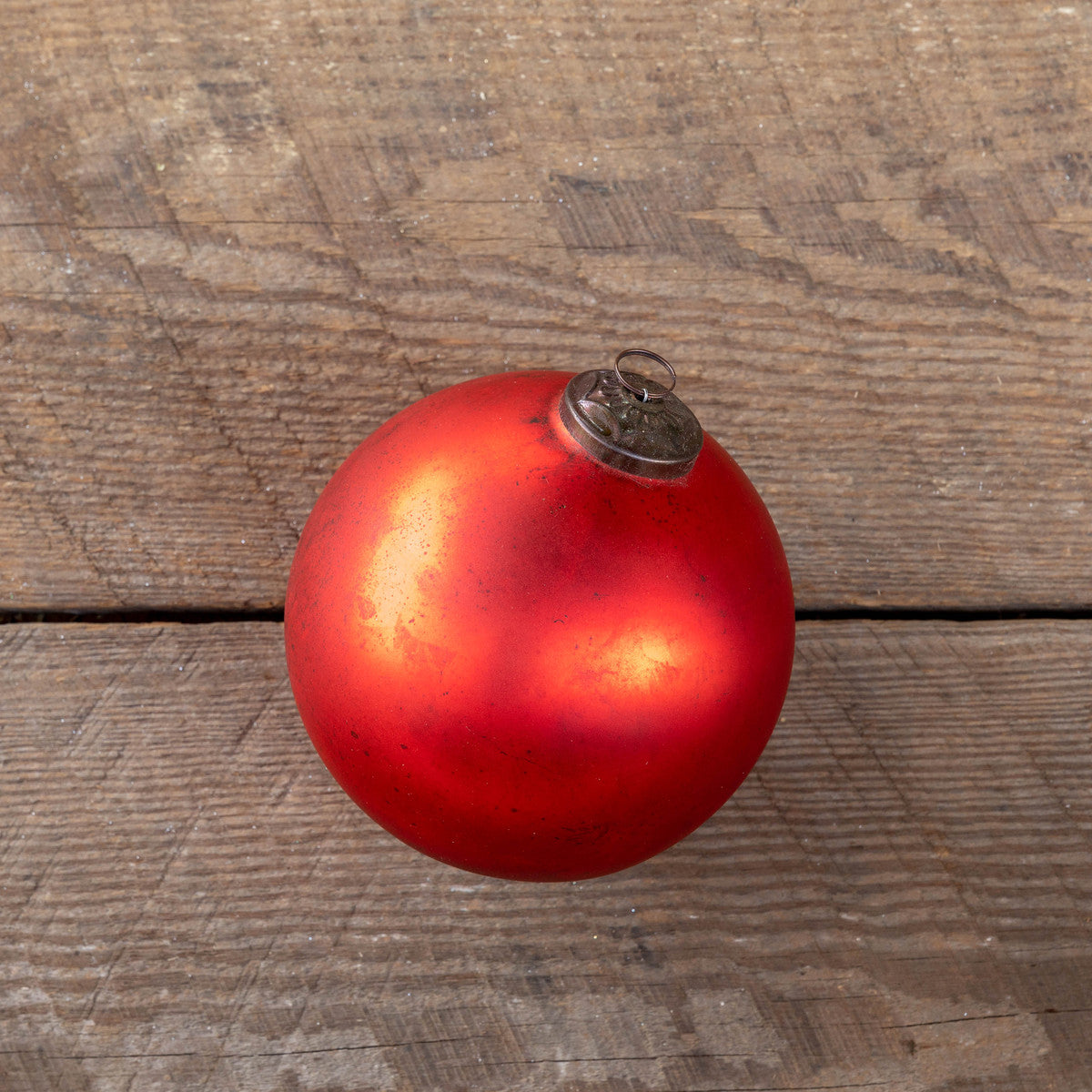 Extra-large antique matte ruby glass ball ornament on a rustic wooden surface.