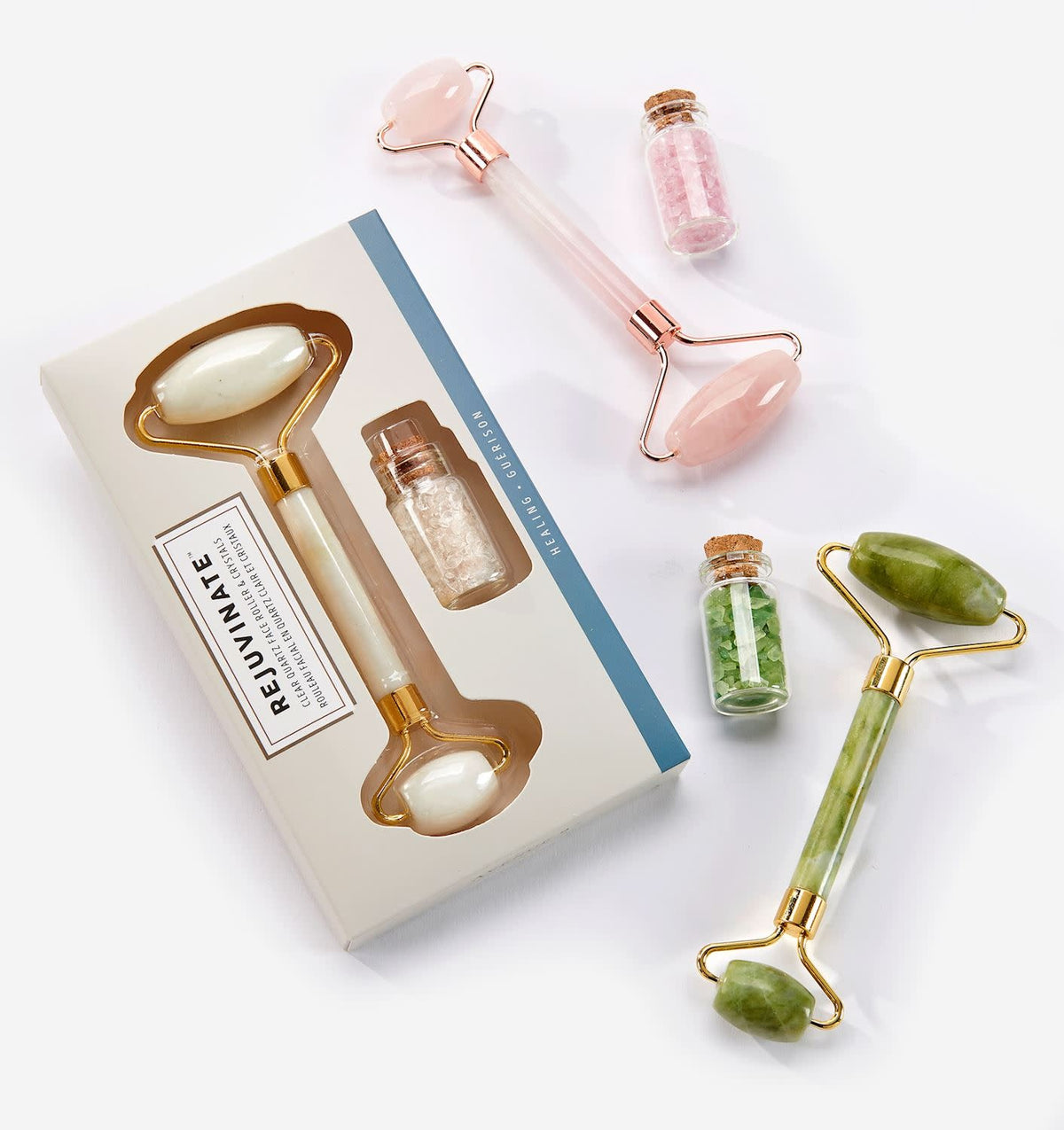 Glass bottle with colorful healing crystals beside an elegant gemstone facial roller.