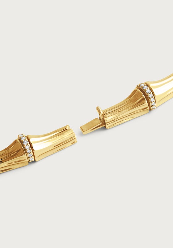 Close-up of a gold-plated bamboo-shaped necklace with crystal pavé accents and a hidden clasp.