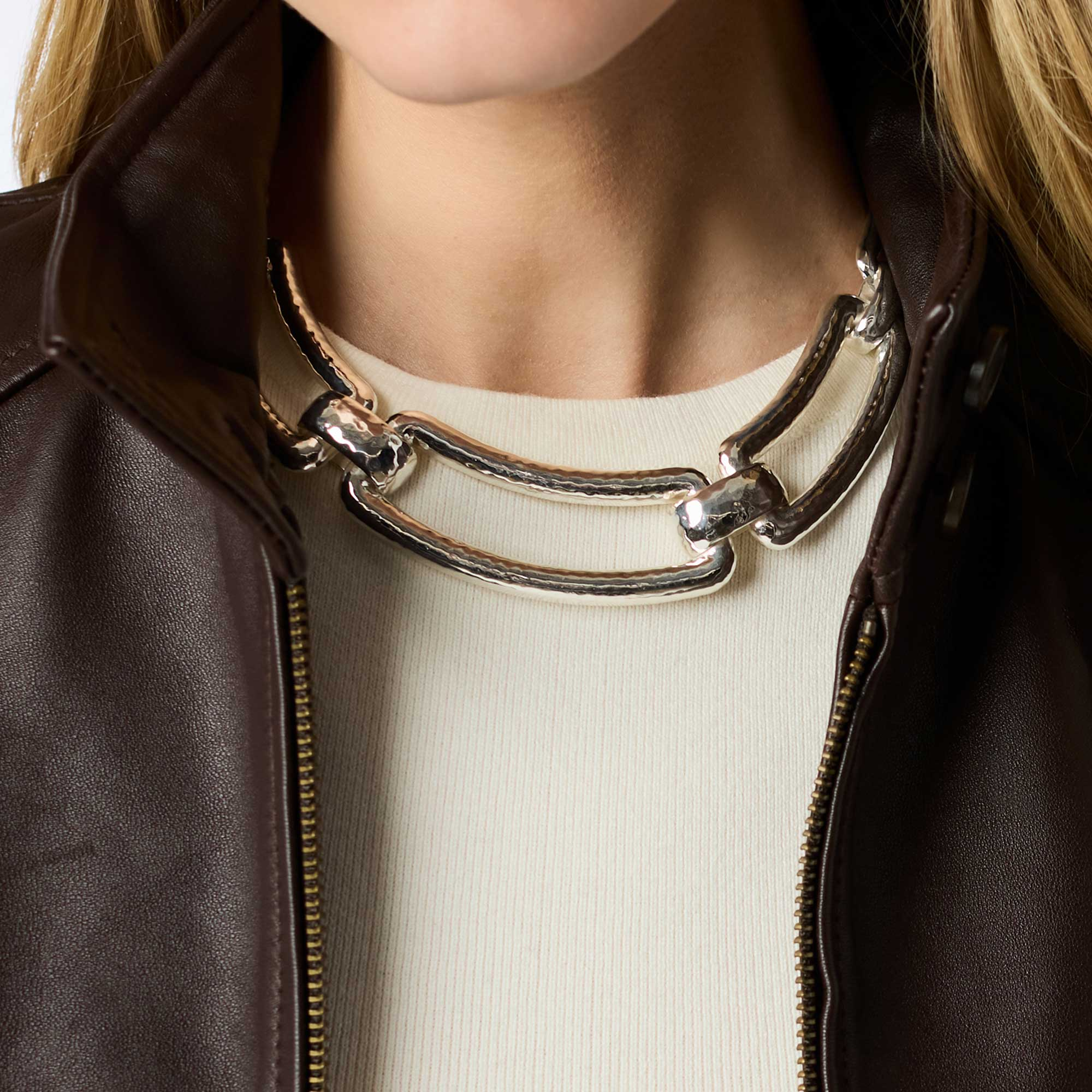 A woman wearing the Sahara Collar Necklace in silver with a brown leather jacket.
