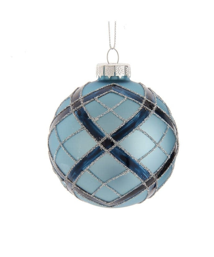 Glass ball ornament with navy plaid pattern on matte blue glittered surface