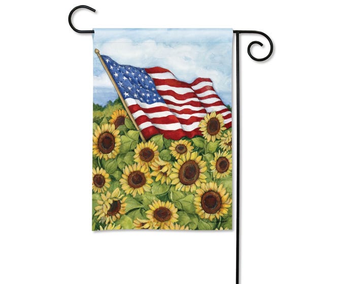 Garden flag with American flag waving over a field of sunflowers.