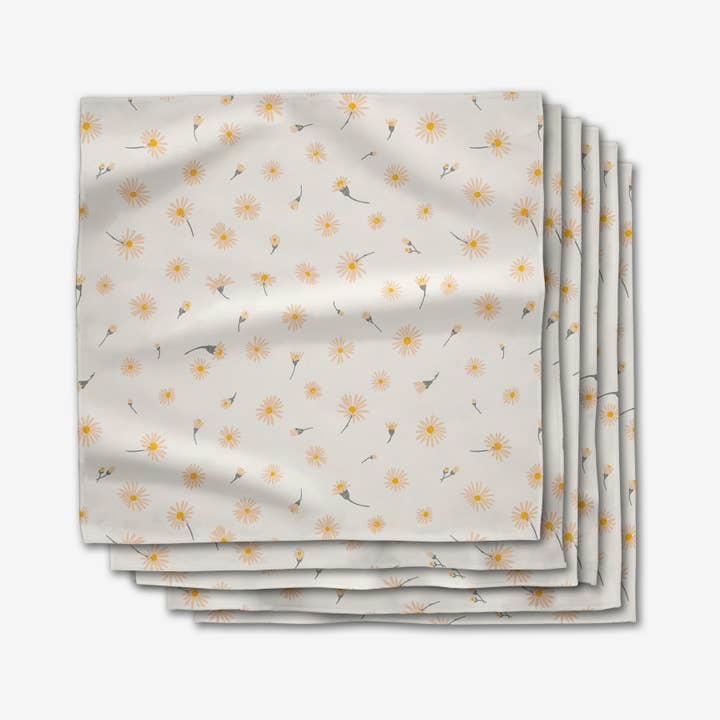 Set of six white dinner napkins with a yellow and orange daisy floral pattern.