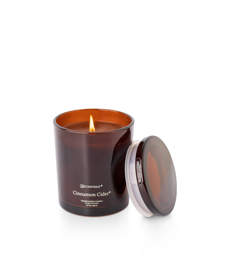 Cinnamon Cider 10 oz candle in a deep amber glass jar with a lit wick and matching lid.