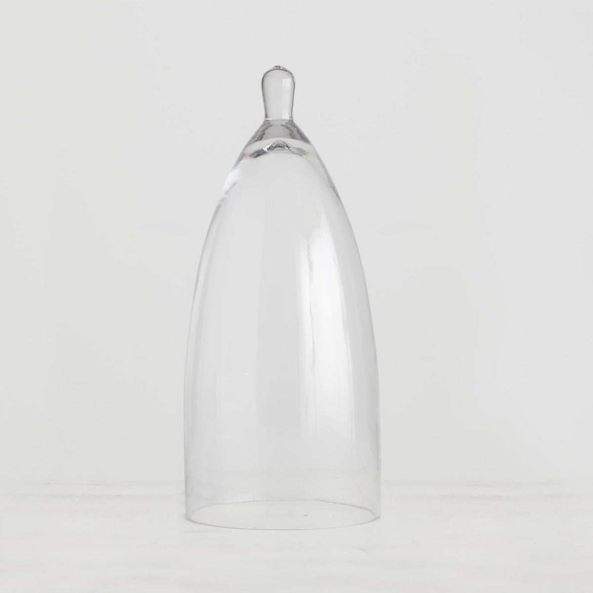 Clear glass cloche with a dome-shaped lid covering an item.