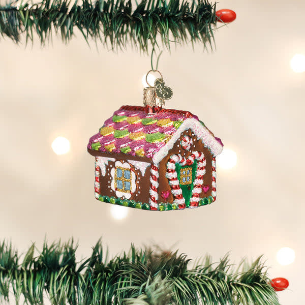 Gingerbread house ornament with candy decorations in brown and red tones.